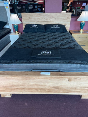 Black mattress with brand logo on a wooden platform in a store setting